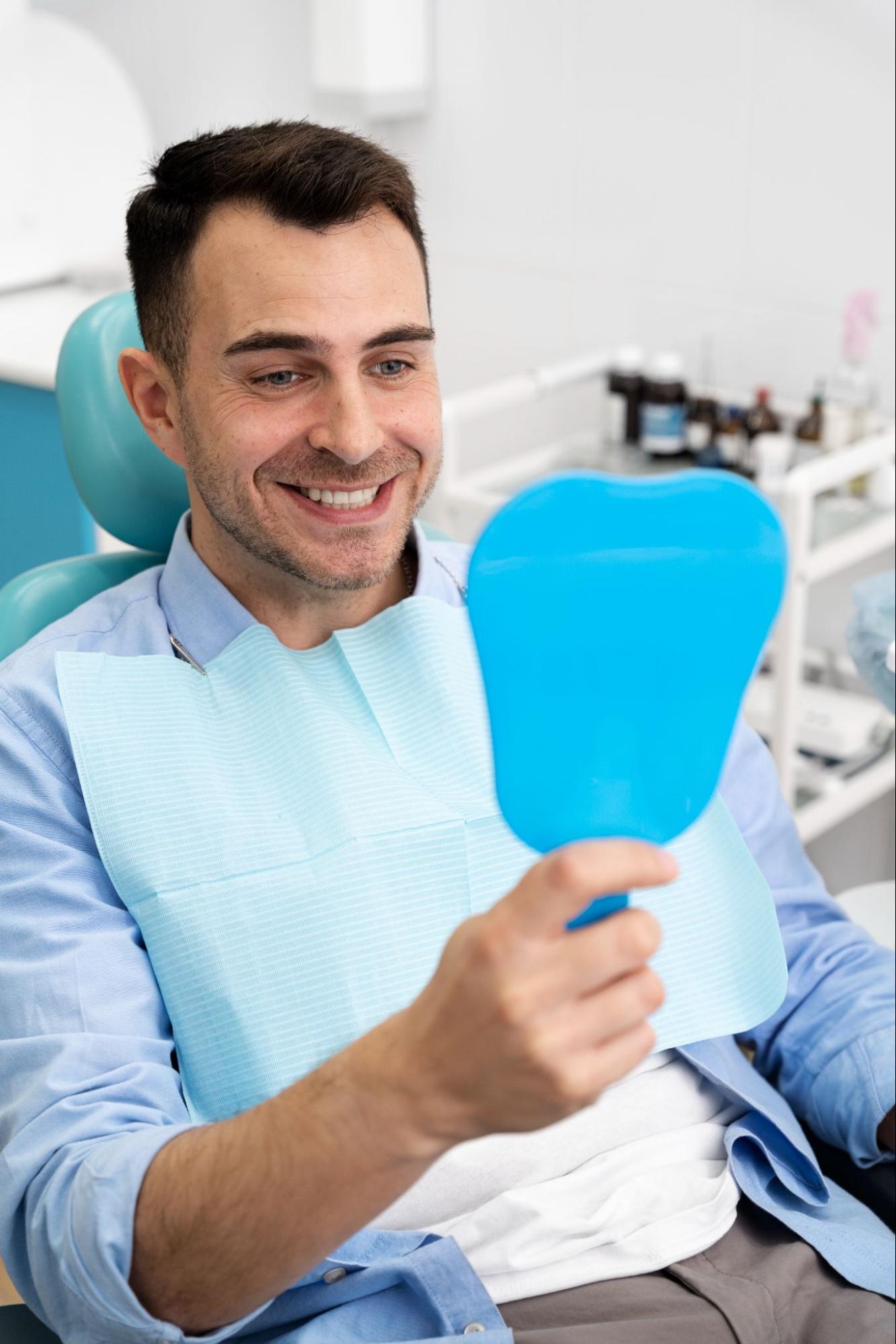 a man sitting on the dental chair smiling through the mirror