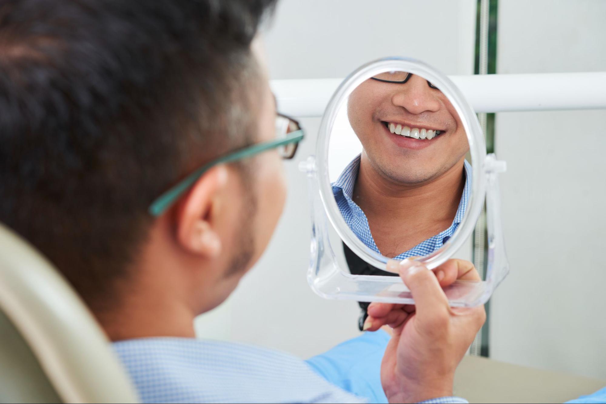 patient at dentist checking his teeth in the mirror