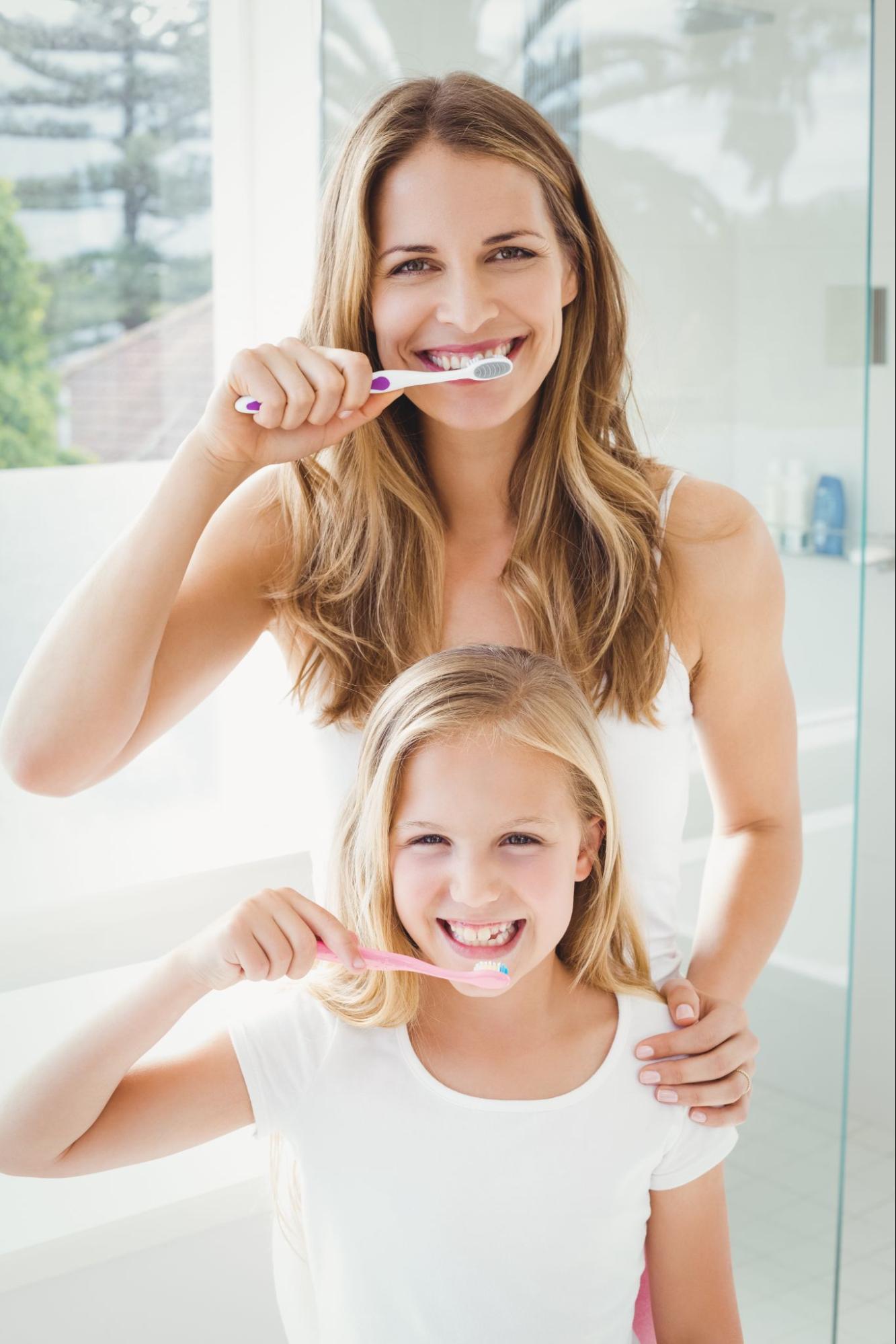 mum with daughter brushing teeth concept